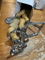 Four pastry tools with wooden handles and steel cutting edges shown partially in and outside a box on a wooden surface.