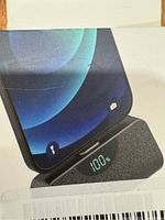 Close-up of power bank digital display showing 100% charge with smartphone on top.