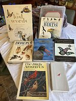 Photo showing all seven books arranged on a table, front covers visible including titles and bird images.