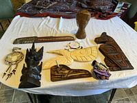 Overview of the lot showing all carvings, 2 dream catchers, and the cloth doll on a white tablecloth.