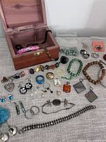 Overview of assortment of costume jewelry pieces and cedar box on surface