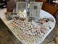Wide-angle photo showing many small containers and bottles of seed beads, as well as tools and bead boards arranged on a table.