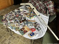 Full display of the lot on table, showing the autographed goalie stick, bobbleheads, many sports cards, packs, and cards boxes.