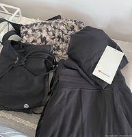 Four women's Lululemon items including black top, patterned handbag interior, and black pants.