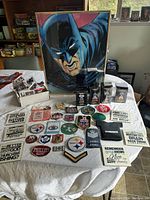 Lot arranged on table showing framed Batman print, fabric patches, magnets, miniature trophies in boxes, and sports cards in box.