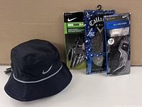 Photo showing the black Nike bucket hat alongside two pairs of golf gloves in packaging: Nike Tour Classic and Callaway Rain Series.