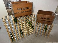 Two vintage Palm Victoria wooden crates placed on top of two wooden lattice-style wine racks, several wine bottles stored inside the racks.