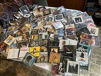 Photo showing a large spread of over 100 CDs mostly rock genre laid out on a surface, various cases and cover designs visible.