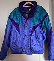 Front view of vintage Descente mens ski coat in purple, teal, and blue with zip and snap buttons.