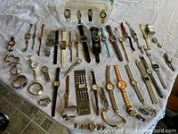 Top-down view of all 48 ladies watches displayed on white cloth, showcasing variety in style and band materials.