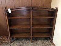 Full front view of antique wooden curved top shelving unit showing three shelves on each side and visible scratches.