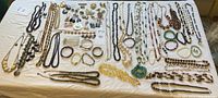 Full spread of costume jewelry on a white cloth, including multiple necklaces, bracelets, earrings, and brooches with various stones.