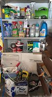 Shelf with various cleaning and garden chemical bottles and containers, including Roundup, Spray n Wash, Mop n Glow, and other products.