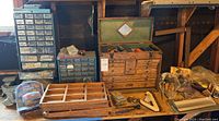 Photo of two metal machinist parts cabinets with many small drawers, a wooden tool chest, and various tools and hardware spread on the floor.