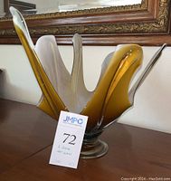 Front left angle view of the mid century modern hand-blown art glass sculpture showing amber and white coloration and organic upward flowing shape.