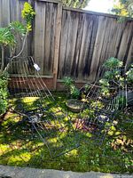 Two black metal wire rocking lounge chairs with round bases set outdoors on mossy brick surface.