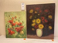 Photo showing both oil paintings side by side on a white surface, one with floral bouquet in vase and dark background, the other with red flowers on green background.