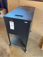 Front angle of the black SAFCO metal rolling cart showing casters and lower shelf