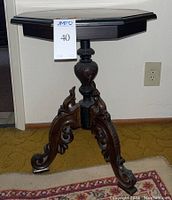 Front view of the antique octagonal side table with carved legs and contrasting wood tones.