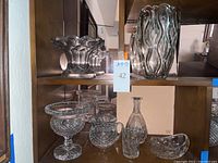 Full assortment of vintage clear glass and crystal items including vase, bowl with ruffled edge, pedestal bowls, pitcher, decanter without stopper, and a boat-shaped bowl.