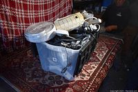 View of plastic bin full of electrical items such as white and beige power strips, coiled white cables, and various power cords.
