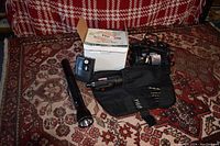 Lot containing Craftsman drill kit including drill, charger, black flashlight, handheld tool, and box of VDO spark plugs on a patterned carpet.