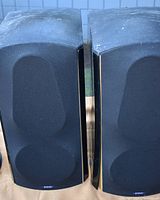 Front view of both black Energy Veritas speakers with fabric grills covering the drivers.