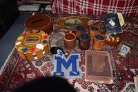 Overall lot of gaming items including Liar's Dice cups, poker chip holder, books, dice, and patch displayed on patterned rug.