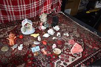 Photo showing array of various small decor items including seashells, figurines of birds and animals, nativity miniature house and figurines, small fabric pouch, small doll figurines and other assorted collectibles arranged on a rug.