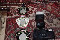 Image showing Nikon camera, Sony flash, and three ceramic picture frames with floral designs on a patterned carpet