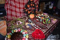 Large table covered by a rug holding various holiday decorations including wreaths, figurines (skeleton, pumpkin), cotton ball hearts, Easter egg decorations, and small pumpkin ornaments.