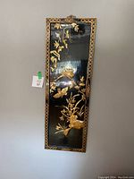 Front view of one rectangular black lacquered wood panel with gold-tone nacre bird and floral design, decorative border, and top hanging hook.