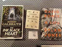 Photo of three books: 'The Ink Black Heart', 'Wenjack', and 'David Bowie: A Life' showing front covers and detail.