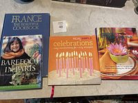 Four cookbooks arranged side by side showing covers: Barefoot in Paris, Real Simple Celebrations, Perfect Entertaining, and France The Beautiful Cookbook.