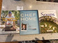 Three cookbooks laid side by side: Jamie Oliver's Food Escapes, The Best of Chef at Home by Michael Smith (signed), and Creative Cooking Soups by Carole Clements.