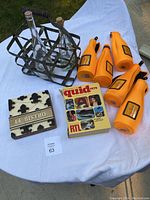 Antique metal bottle rack holding two clear glass bottles with corks, five orange Veuve Clicquot bottle sleeves, Le Bistro sign, and 1979 Quid book