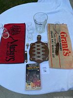 Overview of all items including bar towels, wine pour spouts, glassware, cutting board, and book laid out on white cloth