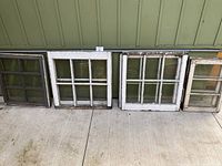 All seven old window panes arranged side by side including grey 6-lite, four 6-lite white windows, and two 3-lite windows.