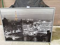 Front view of large black and white framed Paris cityscape print showing Eiffel Tower and river bridges at night.