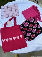 Four items displayed on white cloth: three scarves and one knit tote bag with heart pattern.