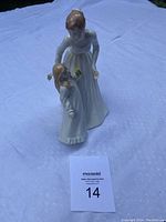 Royal Doulton figurine showing a woman and young child standing close together on a white cloth background, with auction lot card visible in front.