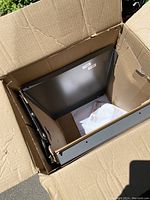 Photo inside open box showing metal frame and packaging for a cabinet pull-out waste system