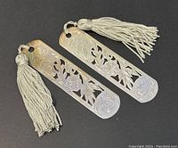 Pair of two Chinese sterling silver bookmarks placed side by side on dark surface with tassels visible