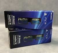 Two sealed boxes of Sony PS3 3D Glasses stacked, front view showing images of glasses and brand names