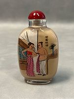Front side of snuff bottle showing a man and woman in an interior scene with calligraphy.