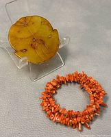 Full view of carved jade pendant and vintage branch coil coral bracelet on display stand