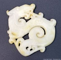Close-up of the hand-carved natural Hetian jade dragon pendant showing intricate details and smooth polish, natural yellow and white color variations visible.