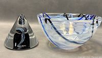 Photo showing the cone-shaped glass paperweight with internal swirls alongside the glass bowl with blue and black patterns.
