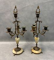 Front view of both vintage metal and stone candlestick holders side by side showing full height and design.
