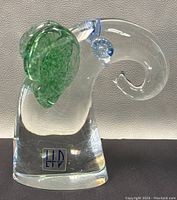 Front view of the signed art glass elephant figurine showing green ears, curled trunk, and artist label on base.